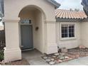 Inviting front entryway with an arched portico, stone accents, and a gray front door featuring sidelight windows at 8349 W Holly St, Phoenix, AZ 85037