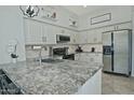 Spacious kitchen features granite countertops, white cabinets, stainless appliances and modern pendant lighting at 10939 N 111Th St, Scottsdale, AZ 85259