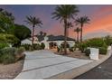 Elegant home with a modern driveway, lush landscaping, and stately palm trees against a colorful dusk sky at 11827 S Montezuma Ct, Phoenix, AZ 85044