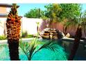 Backyard pool featuring rock waterfall and mature palm trees providing a tropical oasis feel at 15515 N 174Th Ave, Surprise, AZ 85388