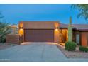 Exterior home view showcasing desert landscaping, outdoor lighting, and a brown two car garage at 16336 E Ridgeline Dr, Fountain Hills, AZ 85268