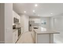 Modern kitchen with white cabinets, stainless steel appliances, gray countertops, a center island, and an open layout at 17758 W Getty Dr, Goodyear, AZ 85338