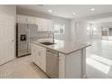 Bright, open kitchen features stainless steel appliances, white cabinetry, a center island with a sink, and tile flooring at 17758 W Getty Dr, Goodyear, AZ 85338