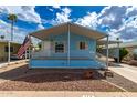 Charming single-story light blue home with a covered porch, landscaped front yard, and American flag at 201 S Greenfield Rd # 144, Mesa, AZ 85206
