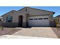 Attractive single-story home with a brick paver driveway, two-car garage, desert landscaping, and welcoming entry at 24493 W Grenadine Rd, Buckeye, AZ 85326