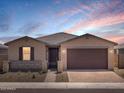 A single-story home during twilight with desert landscaping, a two-car garage, and charming stone accents at 4819 N 177Th Ln, Goodyear, AZ 85395