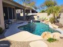 Inviting pool area with a rock waterfall feature, lounge chairs, and lush landscaping at 34687 N 93Rd Pl, Scottsdale, AZ 85262