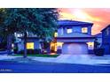 Charming two-story home with a manicured lawn, solar panels, and attached two car garage at sunset at 17394 W Pima St, Goodyear, AZ 85338