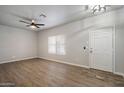 Bright living room featuring wood-look flooring, a ceiling fan, and a large front door at 10551 W Jessie Ln, Peoria, AZ 85383