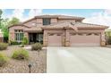Beautiful home featuring a three-car garage, desert landscaping, and an American flag displayed on the facade at 10653 E Lindner Cir, Mesa, AZ 85209