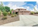 Spacious home with desert landscaping, a three-car garage, and lush trees surrounding the property at 10653 E Lindner Cir, Mesa, AZ 85209