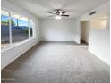 Spacious, carpeted living room with a ceiling fan and a large window offering ample natural light and backyard views at 17405 N 19Th Dr, Phoenix, AZ 85023