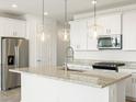 Modern kitchen with granite countertops, stainless steel appliances, and stylish pendant lighting at 17433 W Eva St, Waddell, AZ 85355