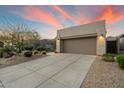 Inviting home with a two-car garage, desert landscaping, and a concrete driveway at sunset at 6522 E Night Glow Cir, Scottsdale, AZ 85266