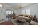 Bright living room featuring hardwood floors, large windows, a beige sofa, and a decorative chandelier at 9837 W Tonopah Dr, Peoria, AZ 85382