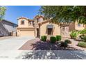 Tan stucco home with stone accents, awning and a well-manicured lawn featuring mature trees at 15620 W Cameron Dr, Surprise, AZ 85379
