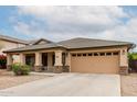 Charming home featuring a two-car garage, covered porch with stone accents, and desert landscaping at 16187 W Gibson Ln, Goodyear, AZ 85338
