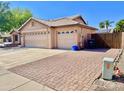 Large three-car garage with a brick-paved driveway and desert landscaping at 1624 E Marigold St, Casa Grande, AZ 85122