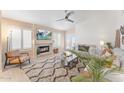 A bright living room featuring a fireplace, plantation shutters, and a ceiling fan at 16823 S 8Th St, Phoenix, AZ 85048