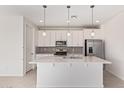Bright kitchen with white cabinets, an island with pendant lighting, stainless steel appliances and tiled backsplash at 18508 E Dario Rd, Gold Canyon, AZ 85118