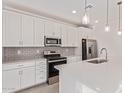 This kitchen has modern white cabinets, stainless steel appliances, backsplash, and an island with a sink at 18508 E Dario Rd, Gold Canyon, AZ 85118