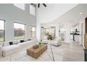 Open-concept living room with a high ceiling, large windows, neutral decor, and seamless flow to the kitchen at 10219 E Le Marche Dr, Scottsdale, AZ 85255