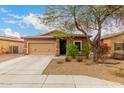 Charming single-story home showcasing a tan exterior, a two-car garage, and desert landscaping at 10835 W Saddlehorn Rd, Peoria, AZ 85383