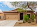Charming single-story home showcasing a tan exterior, a two-car garage, and desert landscaping at 10835 W Saddlehorn Rd, Peoria, AZ 85383