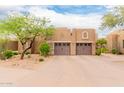 Two-car garage with neutral stucco exterior, stone accents, mature trees, and manicured desert landscaping at 13300 E Via Linda -- # 1065, Scottsdale, AZ 85259