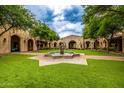 Beautiful courtyard featuring a large fountain, lush green lawn, and arched walkways at 18502 N 98Th Way, Scottsdale, AZ 85255