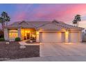 A lovely home with a three-car garage and tile roof is enhanced by desert landscaping and palm trees at 2040 E Indigo Brush Rd, Phoenix, AZ 85048