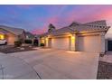 Suburban home featuring a large concrete driveway and a spacious three-car garage under a twilight sky at 2040 E Indigo Brush Rd, Phoenix, AZ 85048