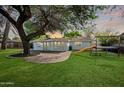 Spacious backyard with a lush lawn, a brick patio area, and a playful slide for outdoor enjoyment at 222 N Miller St, Mesa, AZ 85203