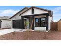 View of a charming single-story home with a black garage door and desert landscaping at 23403 W Albeniz Pl, Buckeye, AZ 85326