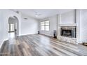 Bright living room with hardwood floors, a ceiling fan, a stone fireplace, and an arched doorway at 4362 W Behrend Dr, Glendale, AZ 85308