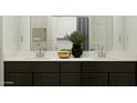 Modern bathroom featuring double vanity, dark wood cabinets, and a decorative mirror and stylish accessories at 5043 S 233Rd Dr, Buckeye, AZ 85326