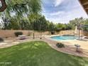 Inviting backyard boasts a sparkling pool, lush green turf, desert landscaping, and overhead string lights at 5513 E Grovers Ave, Scottsdale, AZ 85254