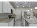 Modern kitchen featuring white cabinetry, stainless steel appliances, granite countertops, and an island sink at 1564 W Redwood Ln, Phoenix, AZ 85045