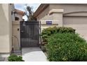 Exterior view of a desert home featuring a decorative wrought iron gate with flowering bushes and cacti at 11390 N 78Th St, Scottsdale, AZ 85260