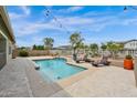 Inviting backyard pool with travertine decking, lounge chairs, and string lights at 1694 E Mia Ln, Gilbert, AZ 85298