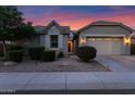 Charming single-story home with well-maintained landscaping and a two-car garage at sunset at 1694 E Mia Ln, Gilbert, AZ 85298