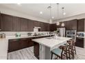 This kitchen features a large island, stainless appliances, dark cabinetry and pendant lighting and light wood-look flooring at 22434 S 226Th Pl, Queen Creek, AZ 85142