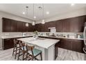 A stunning kitchen features dark wood cabinets, an island with seating and pendant lighting above a white countertop at 22434 S 226Th Pl, Queen Creek, AZ 85142