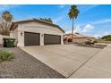Attached three car garage featuring textured walls, desert landscaping, and brown garage doors at 2732 E Hillery Dr, Phoenix, AZ 85032