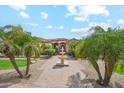 Elegant home entrance featuring a tiered fountain and lush tropical landscaping at 5523 W Creekside Ln, San Tan Valley, AZ 85144