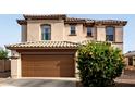 Home exterior with a tan facade, tile roof and brown two-car garage door at 559 W Viola St, Casa Grande, AZ 85122
