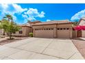 Tan home showcasing desert landscaping, a three-car garage, and a charming tiled roof under a bright blue sky at 1777 W Redfield Rd, Gilbert, AZ 85233