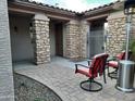 A covered patio space with stone pillars and brick pavers is furnished with outdoor seating at 2487 E Aris Dr, Gilbert, AZ 85298