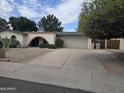 Inviting single-story residence with a driveway, arched entrance, and attached garage at 4718 W El Caminito Dr, Glendale, AZ 85302