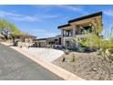 Modern home featuring a three car garage, desert landscaping, and a paved driveway at 9711 N Palisades Blvd, Fountain Hills, AZ 85268
